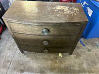 Front view of dark brown three-drawer dresser showing pulls and overall design