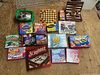 Entire lot spread on floor showing multiple boxed games, chess boards and K'NEX tote