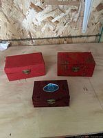 Three closed red brocade boxes with brass clasps