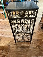 Front view showing metal scrollwork, lion head, and granite top