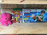 Full view of all three items on shelf: board book set, boxed blaster, plush octopus