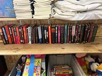 Full shelf of approximately 31 books with magazines above and toys below