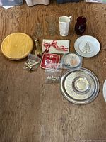 Overview showing wood board, glassware, ceramic holiday dishes, brass hardware bags, silver-plated trays
