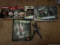 Group shot showing all items: pop-up book, plush set box, Funko Pop box, McFarlane boxed set, loose Michonne figure