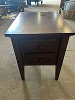 Front view of wooden end table showing two drawers and tapered legs