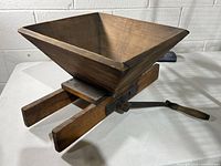 Oblique view of wooden hopper, frame, and crank handle