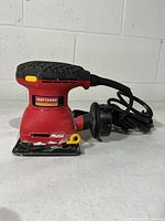 Front left view of Craftsman palm sander showing overall form and coiled power cord