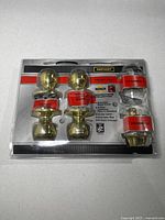 Front view of sealed package showing two keyed entry knob sets and deadbolt components