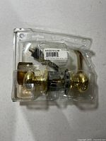 Front view of brass door knob lockset in damaged clamshell