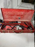 Open metal case showing saw, cord, blades and tray