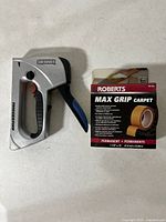 Staple gun and carpet tape box side by side