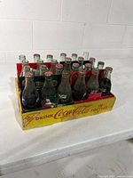 24 Santa edition bottles in four carriers within yellow Coca-Cola tray