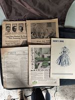 Photo showing several loose vintage magazine pages spread out on a carpeted floor and a small staple-bound booklet titled 'Bride's Book'.