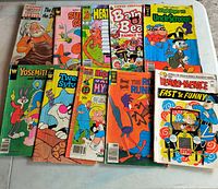 Photo showing all 10 vintage comic books laid out on a white surface, featuring various cartoon characters and titles.