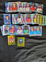 Image of a collection of over 70 soccer trading cards from the 2022 World Cup featuring player portraits and team crests.