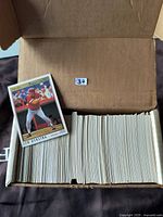 Open cardboard box containing approximately 400 baseball cards mostly from the 1990s, with one card of Len Dykstra displayed on top.