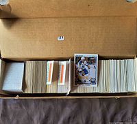 Open box showing neatly stacked hockey cards, mostly 1999 era, with player card visible on top
