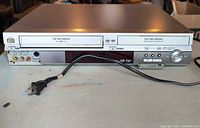 Front view showing DVD and VHS recording slots, power button, and RCA inputs with power cord