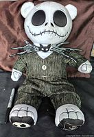 Front view of rare Jack Skellington large plush bear sitting, showing detailed skull face and pinstriped suit with bat bow tie.