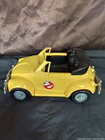 Side view of yellow Ghostbusters convertible toy car with door open, showing Ghostbusters logo.