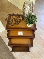 Top view of three nested wooden tables with leather inlay tops, decorative metal bowl, faux plant, and lamp placed on the top table.