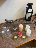 Assortment of candle holders, candles, and glass votives arranged on table