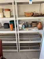 Four Keter plastic garage storage racks of different shelf counts, arranged side by side with ceramic and plastic planters, decorative baskets, and animal figurines on some shelves.