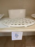 White ceramic oblong container with fitted lid and a lattice-style trivet on a shelf