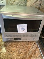 Front view of Panasonic NB-G110P toaster oven on a granite countertop showing control panel, power button, and handle.