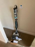 Shark Hz250 upright vacuum with power cord and attachments on the floor against a wall.