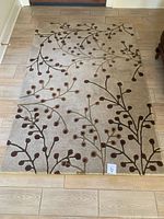 Full view of the Surya 6x4 rug on wooden floor showing its size and branch pattern.