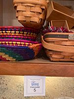 Shelf with various baskets showing a mix of colorful woven round baskets and natural light wooden rectangular baskets including ones with plaid fabric liner.