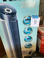 Close-up of boxed Ultraslimline tower fan showing key features including ultra quiet, 4 speeds, eco speed, high performance, and remote control included