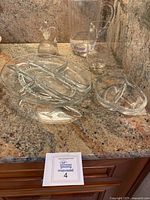 Five pieces of clear glassware on granite countertop: two divided serving dishes and three pitchers of varying sizes.