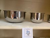 Two polished stainless steel bowls with shiny surfaces and rolled edges, medium and small sizes.