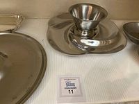 Round metal tray with a hole in the middle holding a metal funnel, alongside a segmented serving tray.