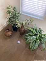 Photo of three vases with faux plant arrangements placed on carpet near window.