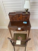 Full view of the vintage secretary desk with the small chair in front, desk features a dark polished wood finish and multiple drawers.