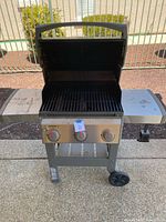 Front view of Weber Spirit II gas BBQ grill with lid open showing cooking grates and front control panel with three knobs.