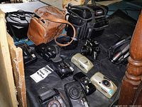 Top view of the lot showing cameras, camcorder, slide projector, and camera bags arranged on a black surface.