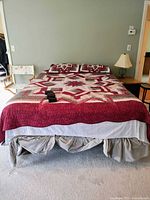 Front view of the queen size bed with patterned quilt and pillows, showing the bedding style and overall bed size.