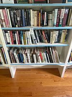 Full view of three bookshelf shelves filled with a variety of books in multiple genres and mixed bindings