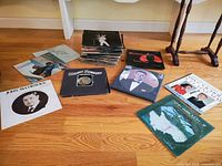 Photo showing a stack and scattered vintage vinyl LP records on floor with visible covers including Frank Sinatra, John McCormack, Mickey Newbury, and others.