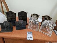 Photo showing all four pairs of vintage bookends on table, including cast iron chief head and bookshelf, glass horse heads, and brass/bronze monk/scholar motifs.