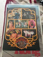 Photo of the poster showing colorful images of the cast from the movie Sgt. Pepper's Lonely Hearts Club Band arranged inside an orange graphic frame on a black background.