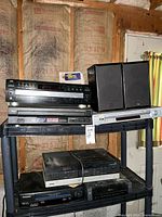 Full view of entire lot showing stacked stereo components and speakers in basement storage area with insulation visible on walls.