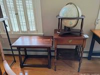 View of the globe on wooden stand and two side tables side by side, showing overall appearance and condition.