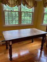Front side view of the rustic farmhouse wood kitchen table showing turned legs and dark stained wood surface.