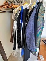 Hanging women's clothing including jackets, coats, dresses, and blazers in various styles and materials, size 12
