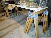 Full view of wooden workbench with tabletop supported by sawhorse legs, showing the setup and height.